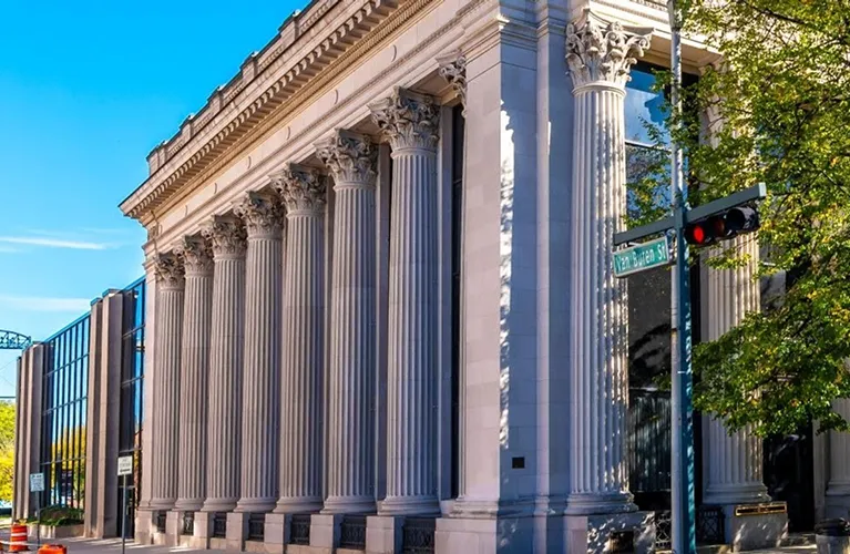 Classical building facade with tall Corinthian columns and a street sign reading "Van Buren St.