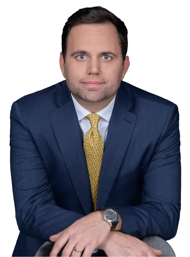 Professional man with dark hair wearing a navy suit, yellow patterned tie, and wristwatch.